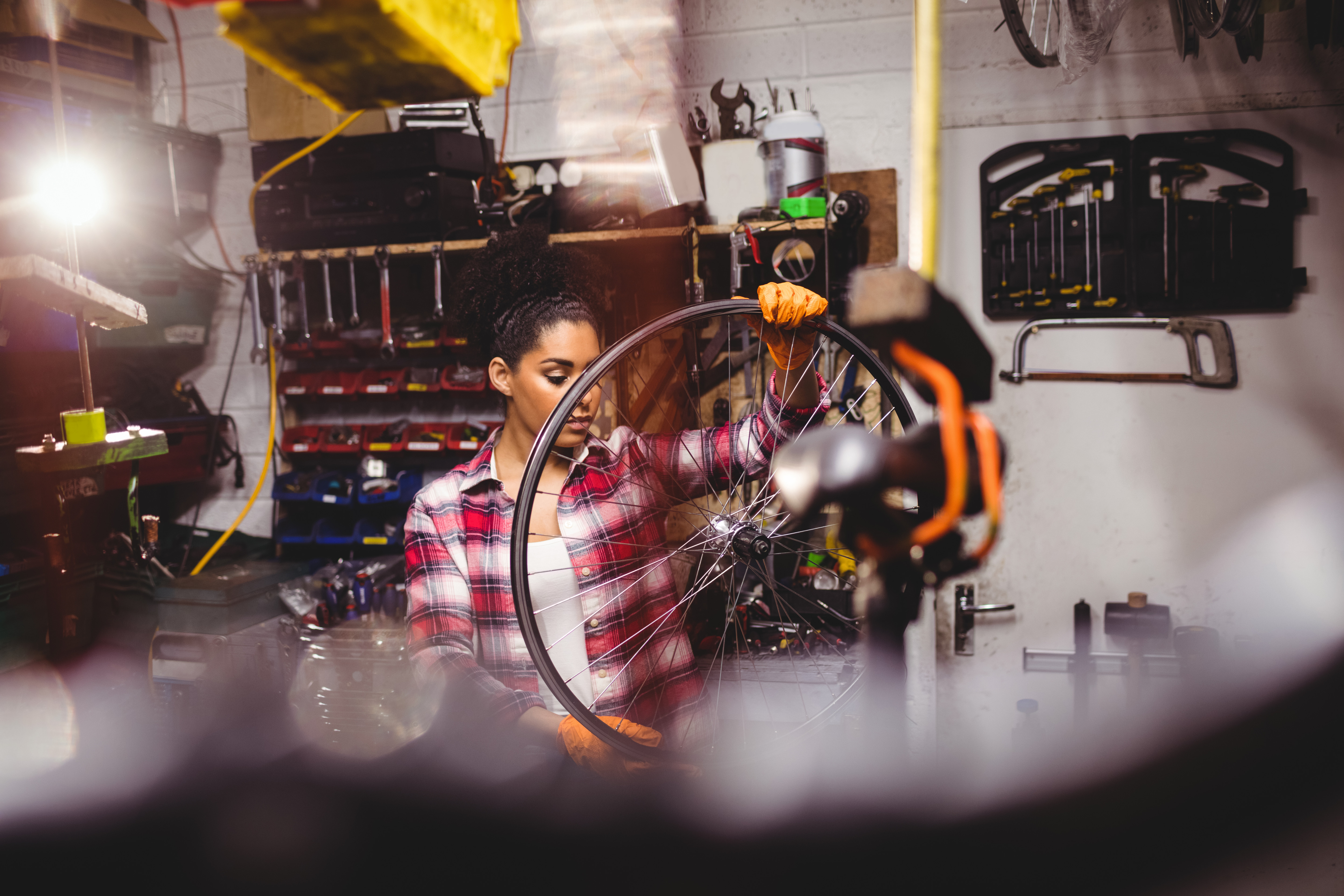 Female bicycle mechanic examining a bicycle wheel in workshop